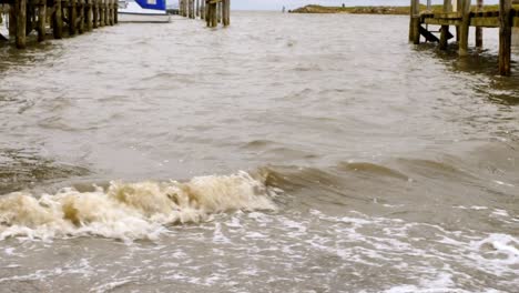 Nahaufnahme-Von-Wellen,-Die-Auf-Den-Pier-Eines-Kleinen-Hafens-In-Rantum,-Sylt,-Treffen