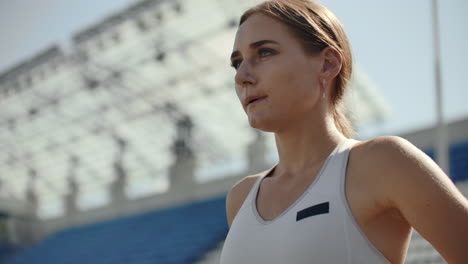 beautiful woman athlete at the stadium breathing and preparing to start the race. motivation and tuning for the race. concentration and attitude