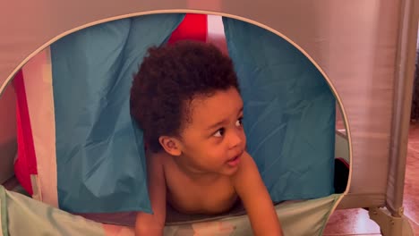 adorable and exotic two year old african european child playing with daddy to hide-and-seek in his toy tent, indoor