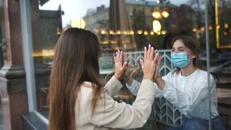 amigos manteniendo la distancia social a través de una ventana