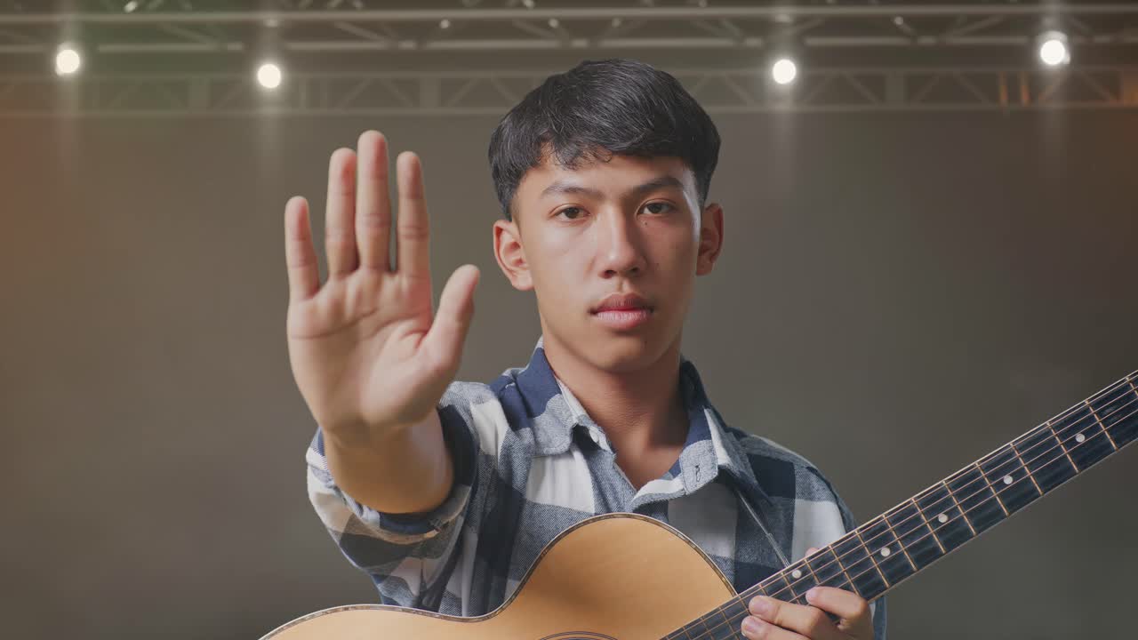무대 위 에 서 있는 동안 기타 를 연주 하는 아시아 청소년 의 근접 사진