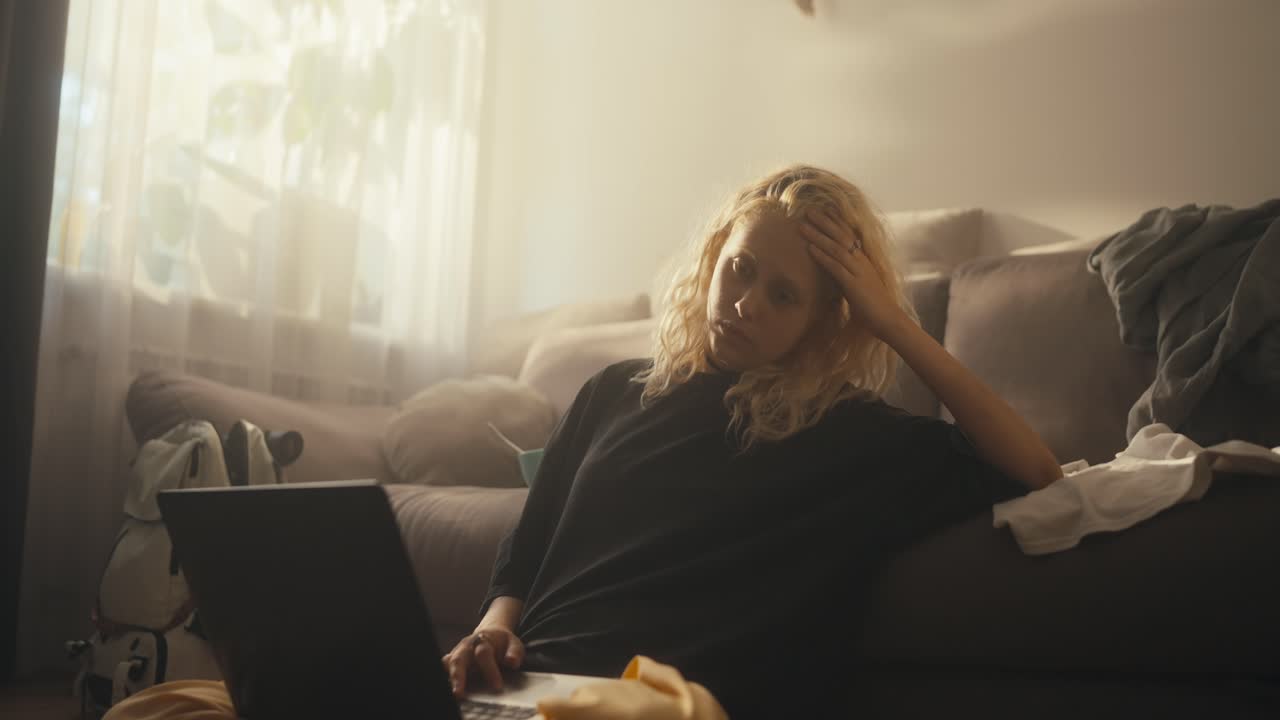 Tired sad blonde girl in a black T-shirt abruptly closes the laptop after watching movies all night at home