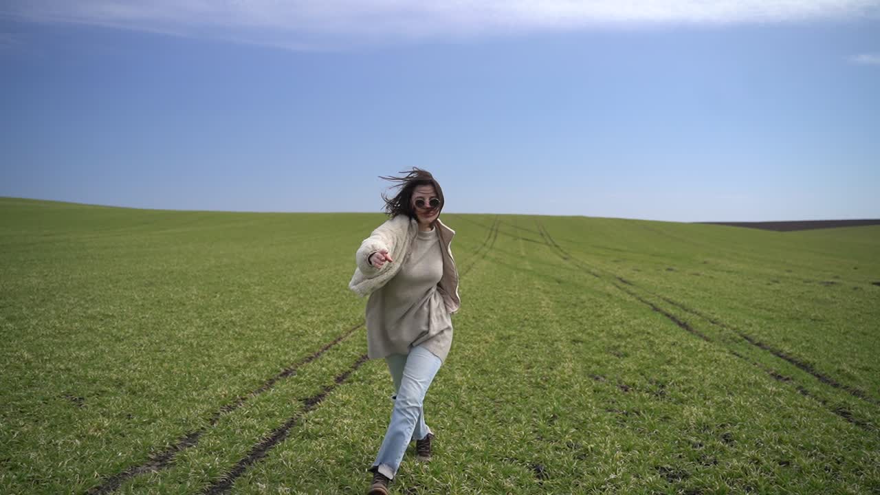 молодая красивая девушка-брюнетка бежит по зеленому лугу.