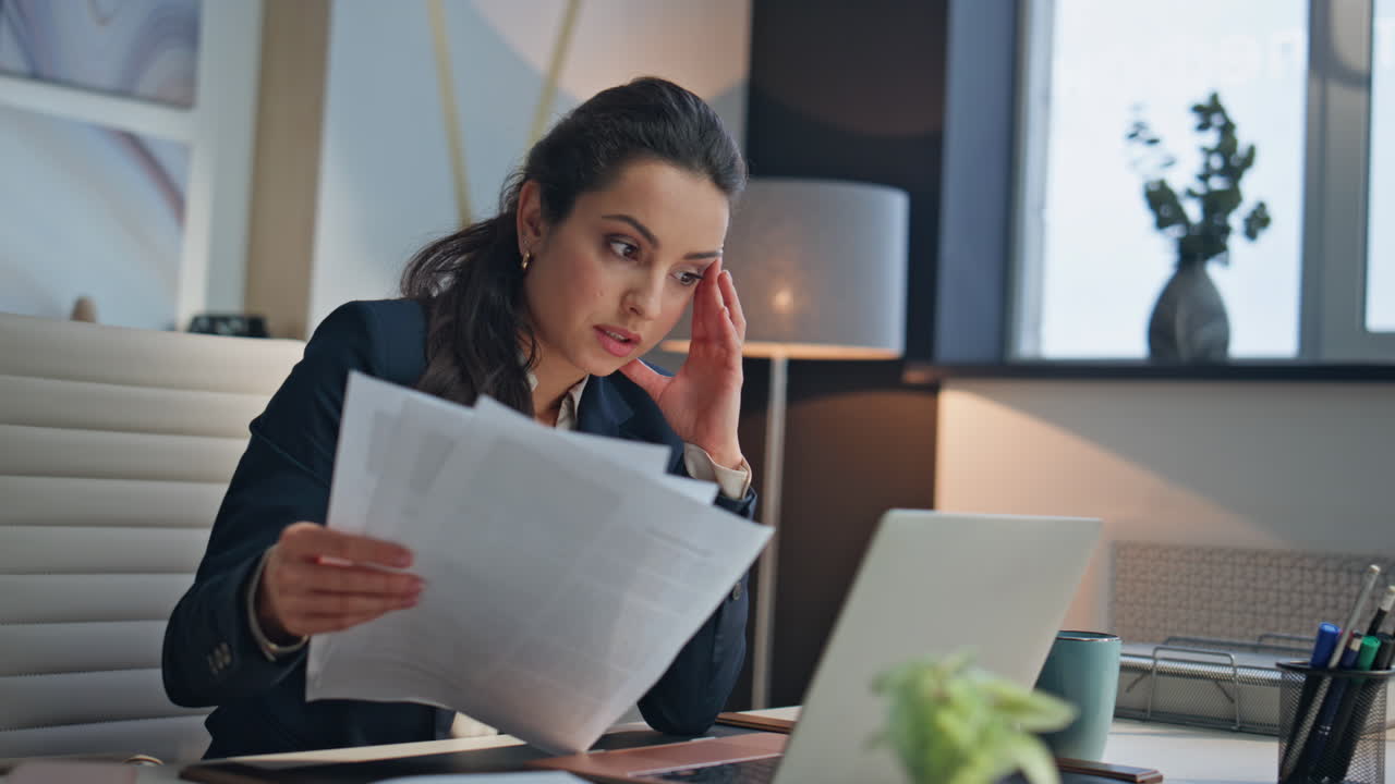 Primo piano in ufficio: dipendente serio che legge documenti. Manager stanco con il laptop chiuso.