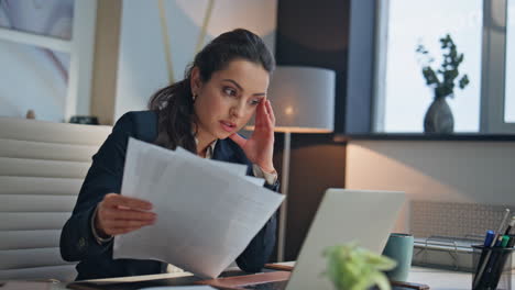Serious employee reading papers in office closeup. Tired manager closed laptop