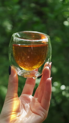 woman holding a double-walled glass cup of tea outdoors