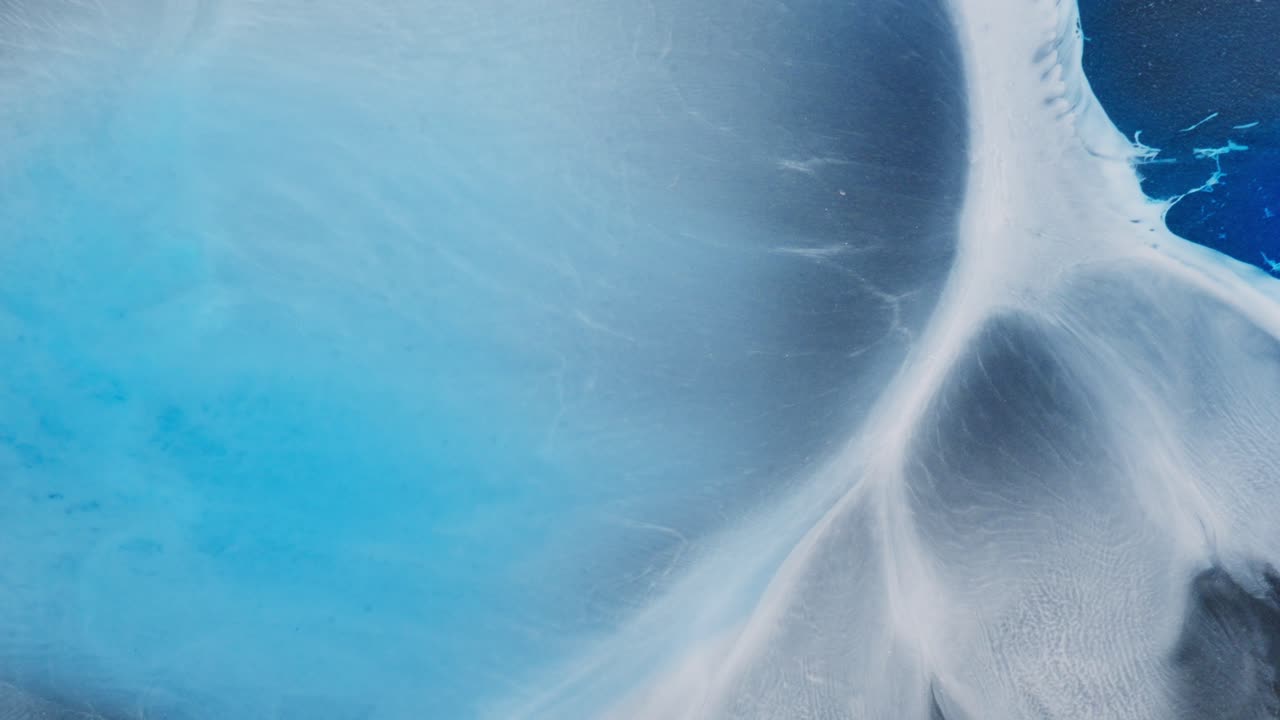 Blue and white alcoholic ink flow in abstract macro shot, forming dreamy organic patterns