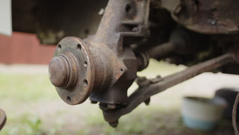 Mechanic-wearing-gloves-removes-rusty-disc-brakes-from-vehicle-axle