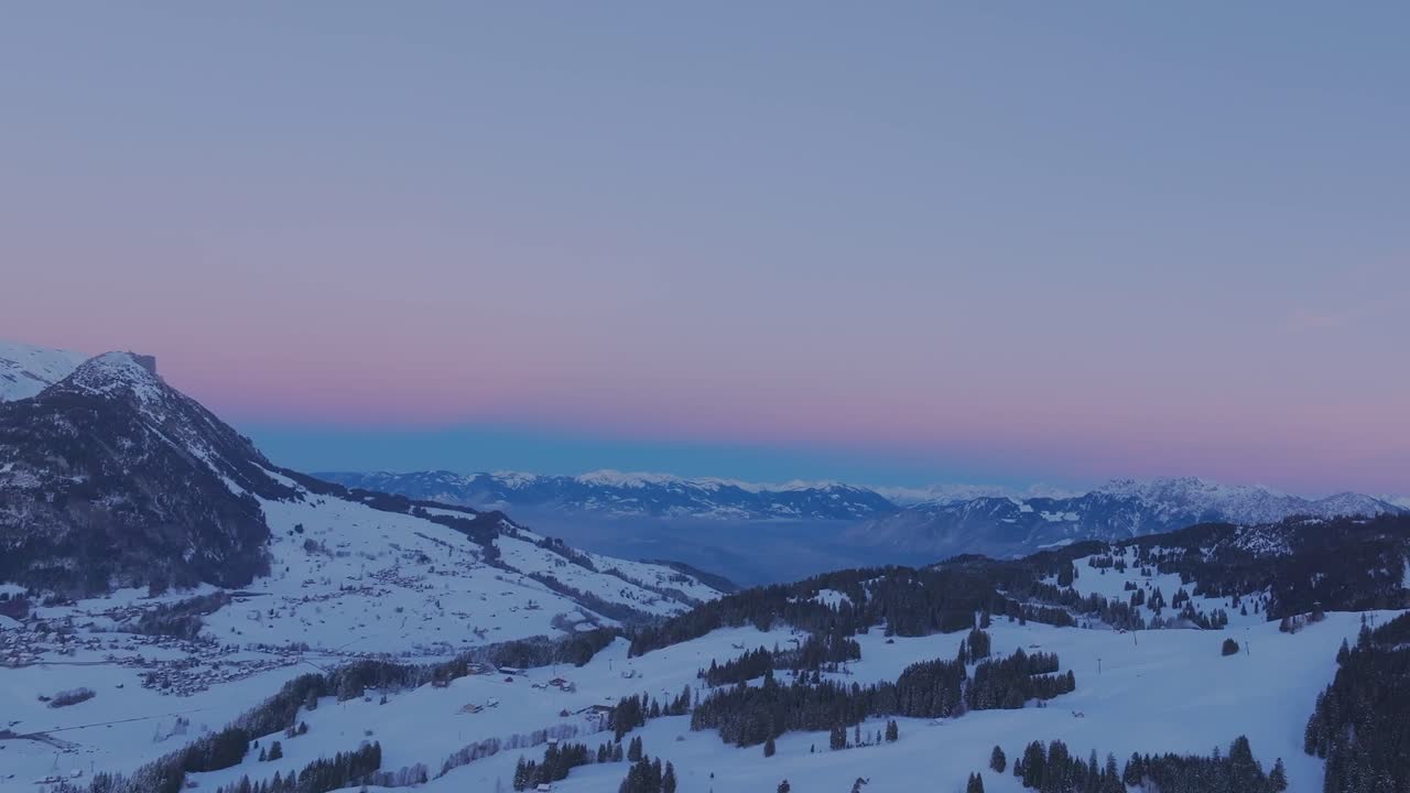 눈 인 산맥의 실루을 비추는 해가 뜨는 평화로운 아름다움을 드러내는 드론 영상