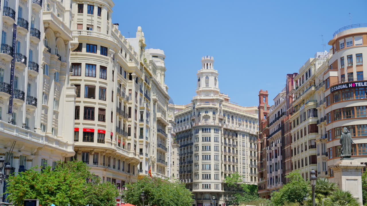 Valencia, Spain - May 29, 2025: Cyclists and pedestrians on a pedestrian boulevard leading toward the landmark towered buildings of Plaza del Ayuntamiento