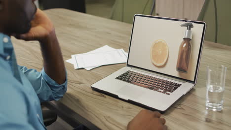 African-american-man-at-table-using-laptop,-online-shopping-for-beauty-products,-slow-motion