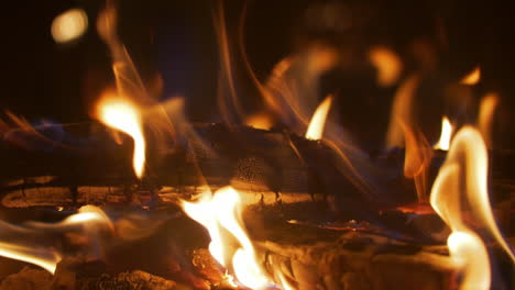 fermer le détail macro des bûches de bois brûlant au ralenti, glissant vers la gauche