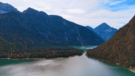 gorgeous mountains covered by the pine tree forests surround a beautiful lake. top perspective on lake plansee, reutte district, tyrol, austria.