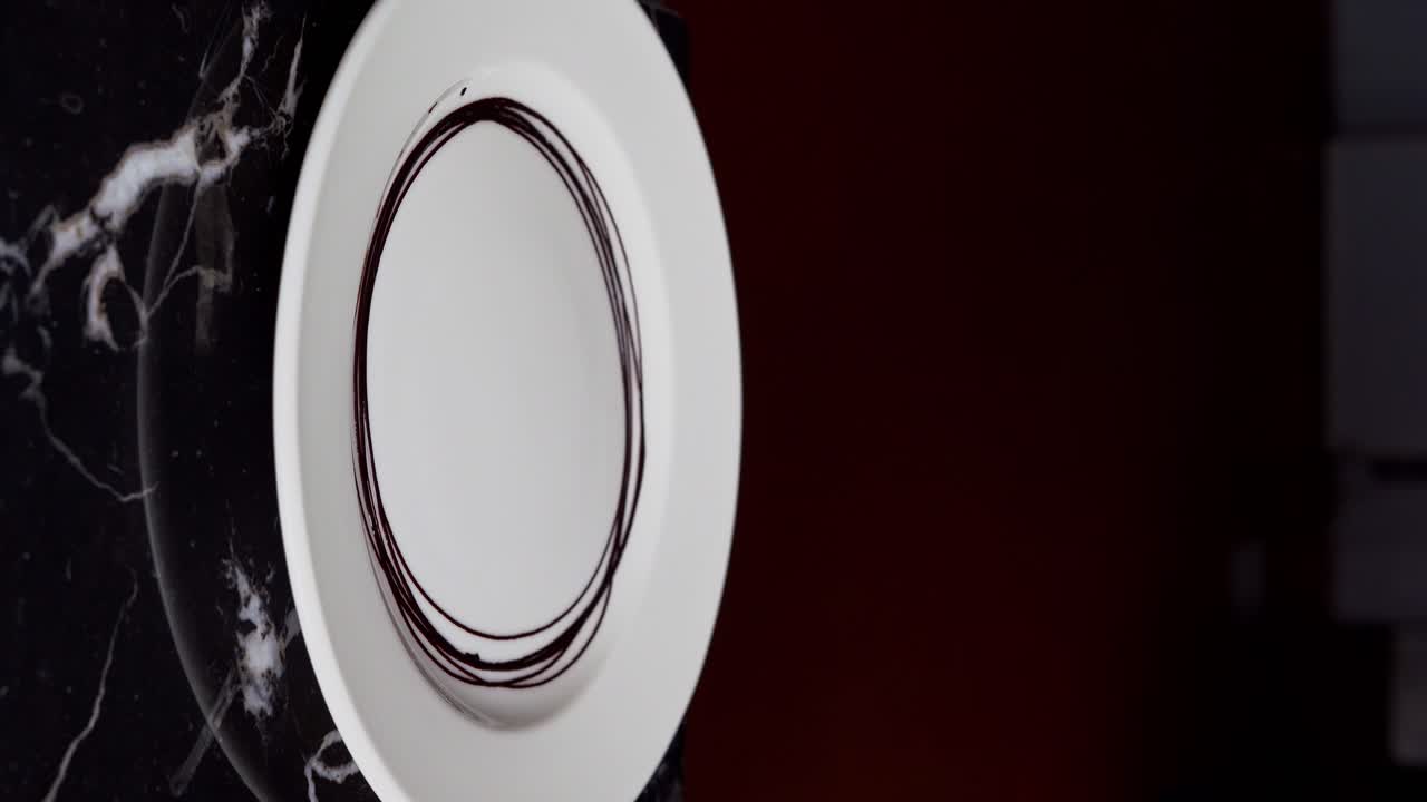 A Chief prepares a chocolate plate with chocolate sauce, close up shot, insert shot, vertical video