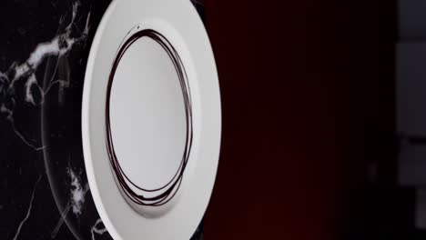 a chief prepares a chocolate plate with chocolate sauce, close up shot, insert shot, vertical video