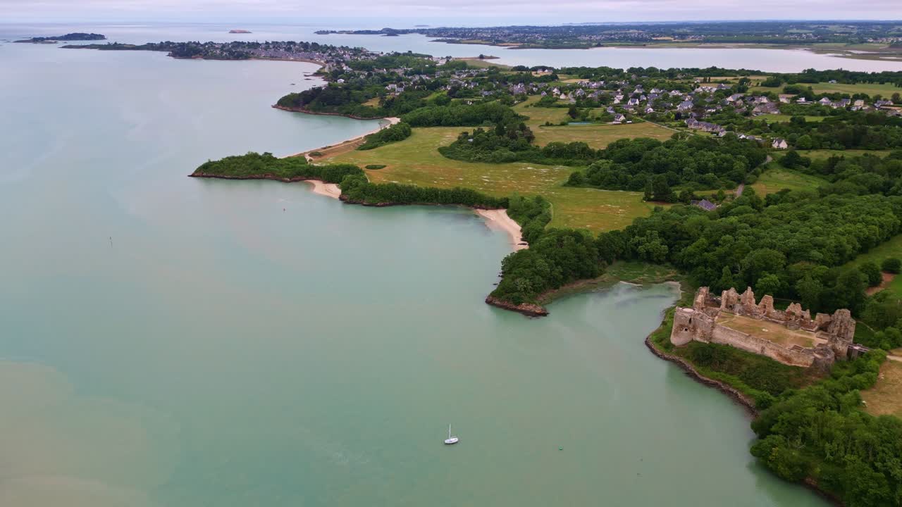 Historic ruins of Château du Guildo castle at mouth of Arguenon river, Brittany coastline, Saint-Jacut-de-la-Mer, France. Aerial drone backward