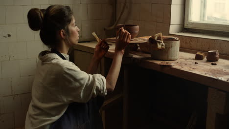 joven artista usando herramientas en el taller. ceramista decorando una olla de arcilla en el estudio