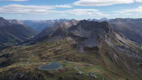 Un-Increíble-Horizonte-Montañoso-Con-Un-Cielo-Azul-Brumoso-Salpicado-De-Nubes-Y-Un-Pequeño-Camino-Sinuoso-Al-Pie-De-La-Montaña,-Cerca-De-Los-Lagos-Körbersee-Y-Kalbelesee,-Austria