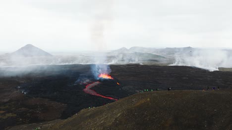 aerial landscape view of many people looking at the volcanic eruption at litli-hrutur, iceland, with fresh lava and smoke coming out