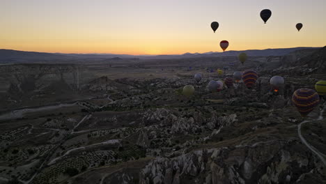 Göreme-Turquía-Aérea-V45-Paisaje-Del-Amanecer-Que-Captura-Formaciones-De-Roca-Volcánica-Surrealistas-Con-Una-Aventura-Turística-En-Globos-Aerostáticos-Que-Se-Elevan-Hacia-El-Cielo-Al-Amanecer---Filmada-Con-Cine-Mavic-3---Julio-De-2022