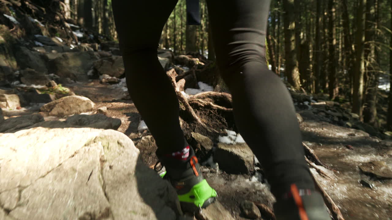 Boots with crampons of a woman hiking in a snowy forest. Slow motion