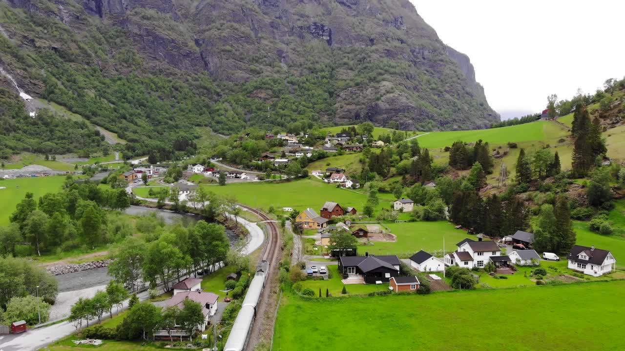 antena: tren flåm atravesando un valle entre verdes prados y junto a un río