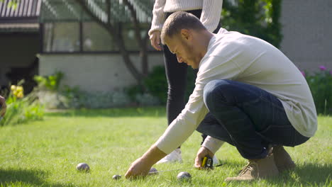 side view of a caucasian young man calculating distance between petanque balls in the park