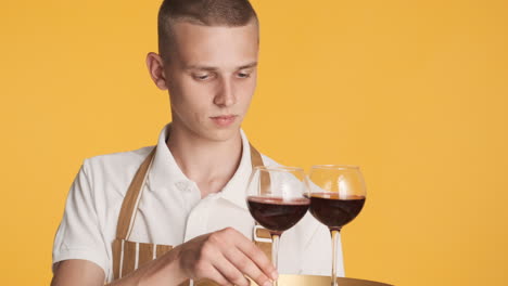 joven en uniforme de camarero con copas de vino