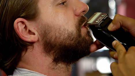 barber trimming mans mustache with trimmer at barber shop 4k