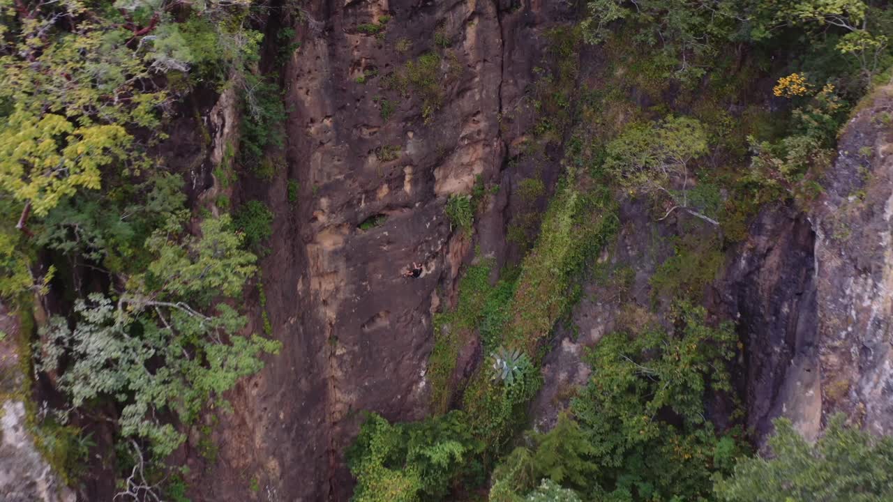 vista de un avión no tripulado de una persona bajando en rappel por la pared del acantilado