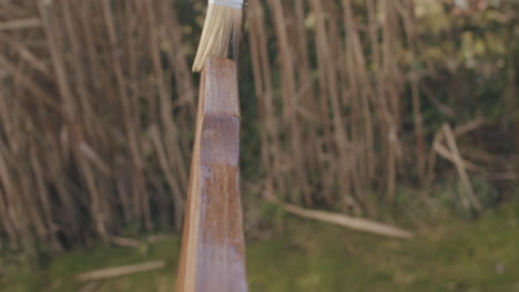 close-up shot van het aanbrengen van lijnolie op een houten stoel met een borstel