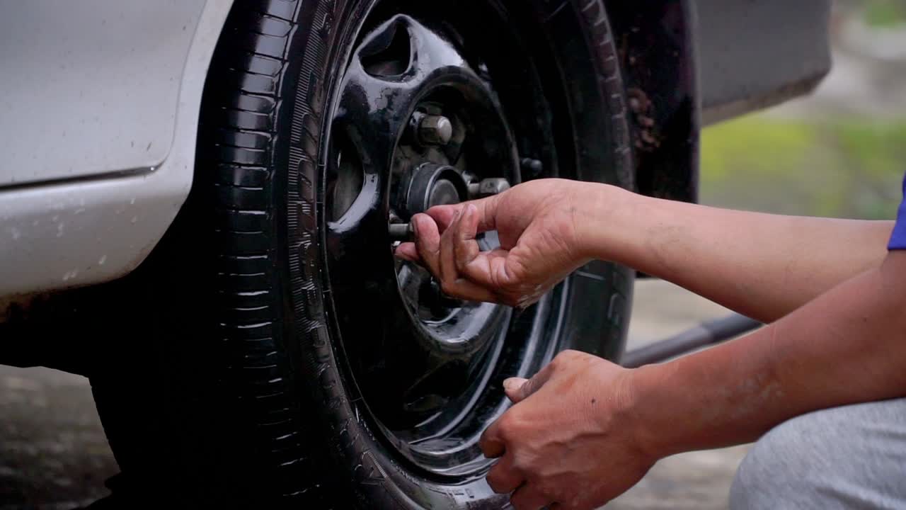 Close up shot of man hand fit the nut on the car tyre after replace the tyre