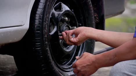 Primer-Plano-De-La-Mano-Del-Hombre-Coloque-La-Tuerca-En-El-Neumático-Del-Automóvil-Después-De-Reemplazar-El-Neumático