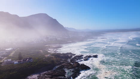 Drone-pullback-reveals-slight-mist-hanging-over-Voëlklip-in-Hermanus