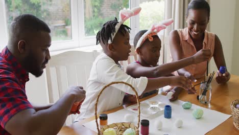 african american family painting easter eggs together at home