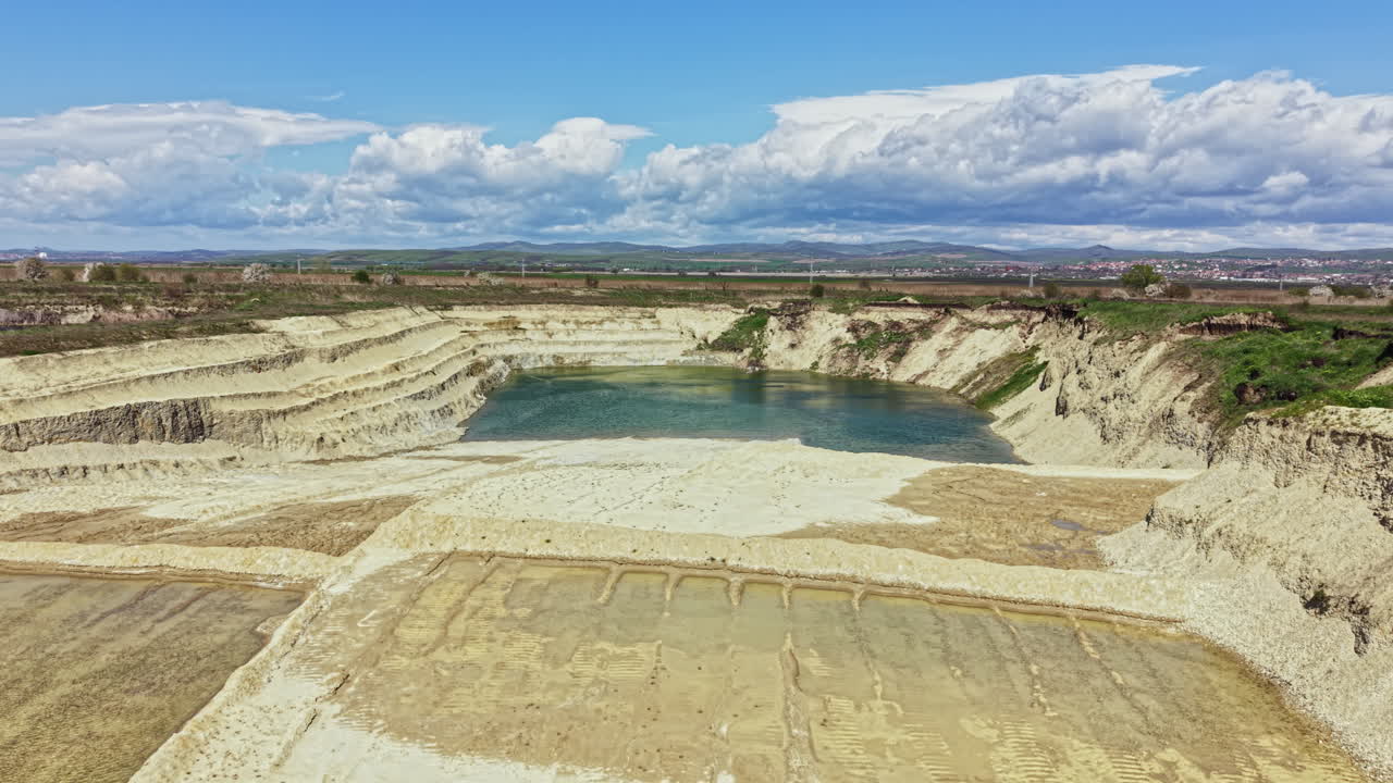 View of the sandy lake surrounded by cliffs in a rural area with blue sky and clouds on a sunny day in the afternoon