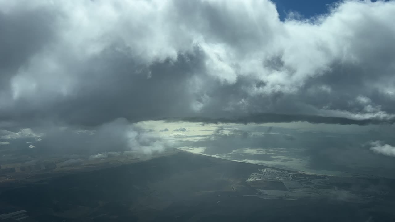 punto de vista del piloto desde la cabina de un jet volando sobre el gufl de cádiz, españa, durante el descenso a través de algunas nubes estratos