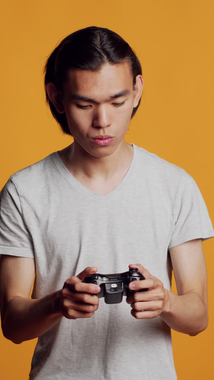 Vertical video: Modern asian man playing videogames on console
