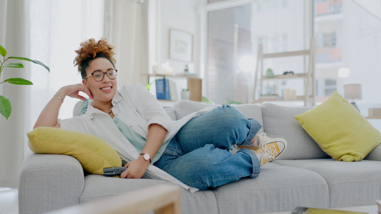 mujer, relajarse y ver la televisión en el sofá en la sala de estar