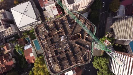 drone-footage-top-view-of-a-construction-site-with-a-huge-crane-on-top-of-a-skyscraper-in-the-city-of-buenos-aires