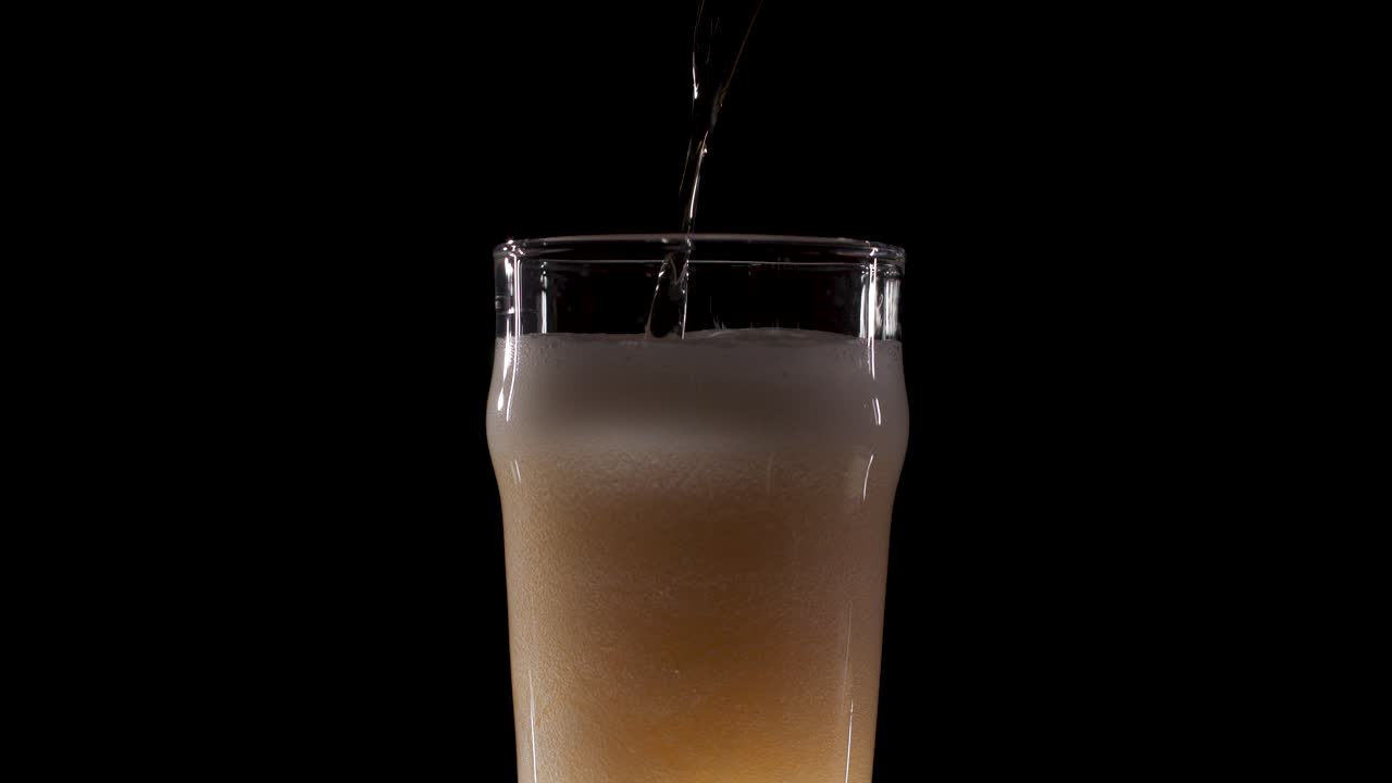Beer on black background poured with a lot of head in slow motion
