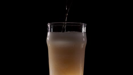 beer on black background poured with a lot of head in slow motion