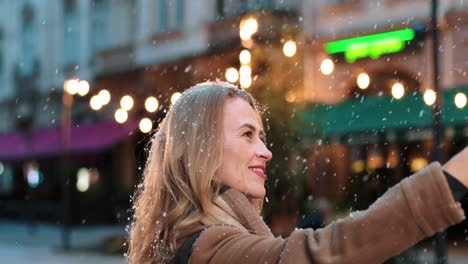 close-up view of caucasian woman making a selfie with smartphone on the street while it‚äôs snowing in christmas