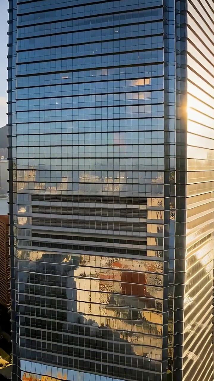 Video vertical: Cámara en paneo capturando una torre de cristal en el puerto, mostrando bandas de ventilación y reflejos en movimiento.