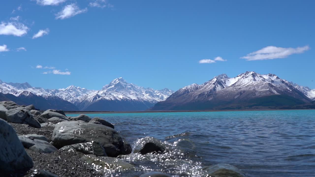 agua salpicando junto a la playa en el lago pukaki con el monte cook al fondo