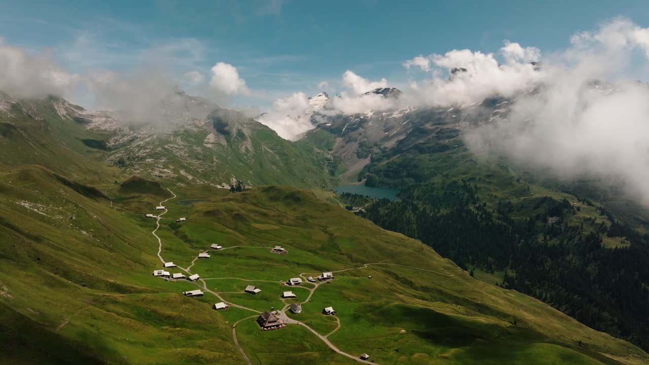 Aerial drone shot of alpine village and valley landscape with a distant mountain lake in Melchsee-Frutt, Switzerland