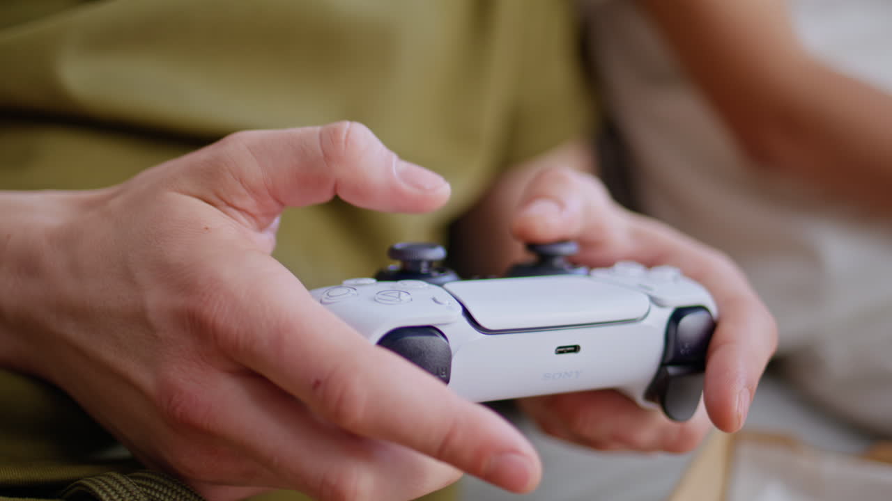 Guy fingers playing videogame sitting couch living room closeup. Teenager hobby