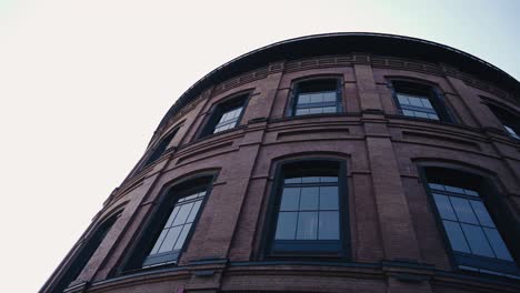 the building is in the shape of a cylinder made of brown brick. modern urban architecture.