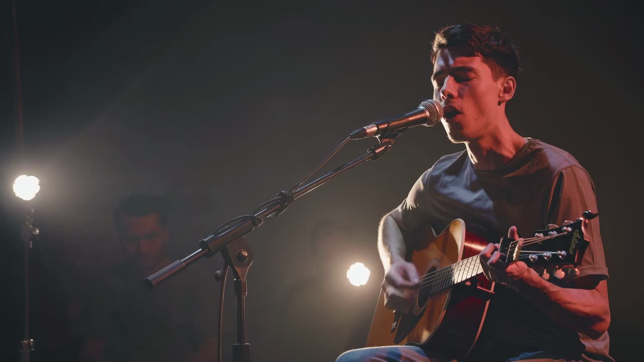 A close-up, low-angle video captures a musician passionately singing and playing guitar on stage