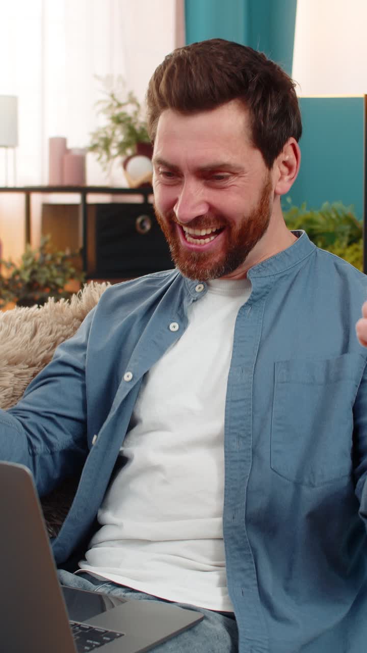 Young man happily clapping hands in front of laptop celebrating good news or online competition win